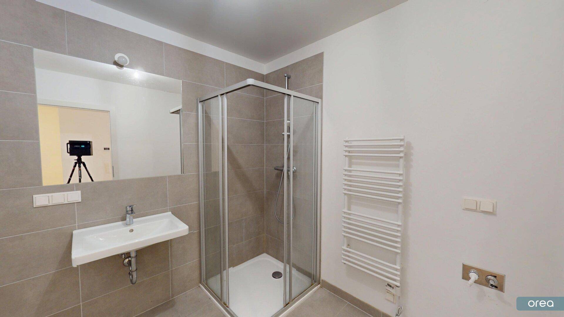 Modernes Badezimmer mit Eckdusche, Einzelwaschbecken und beheiztem Handtuchhalter.