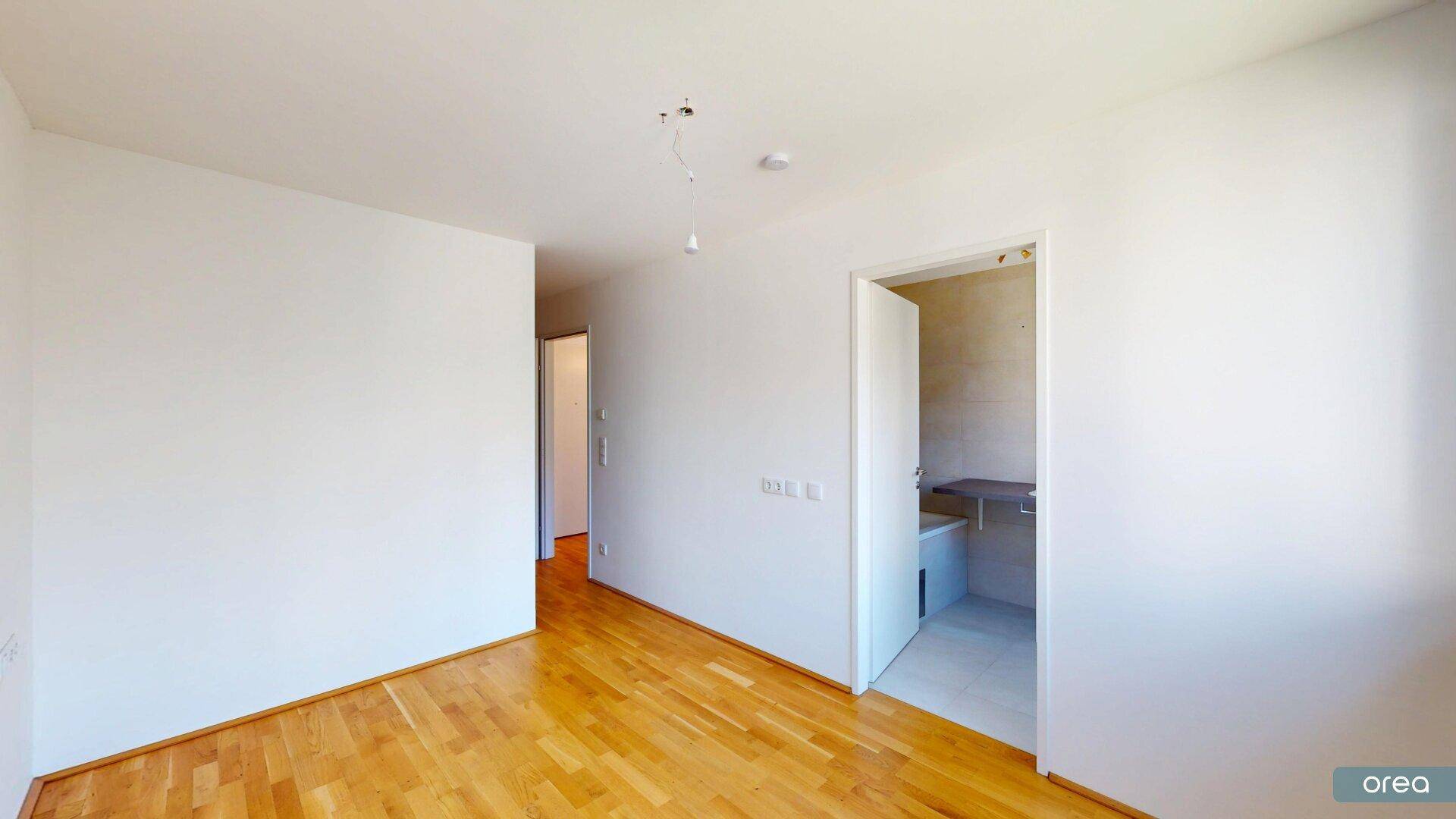 Heller Flurbereich mit Holzboden, der zu weiteren Räumen und einem Badezimmer führt.
