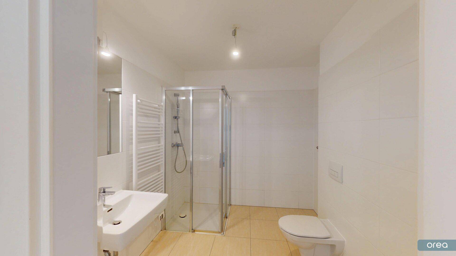 Modernes Badezimmer mit Duschkabine, wandhängendem WC, Waschbecken und beheiztem Handtuchhalter.