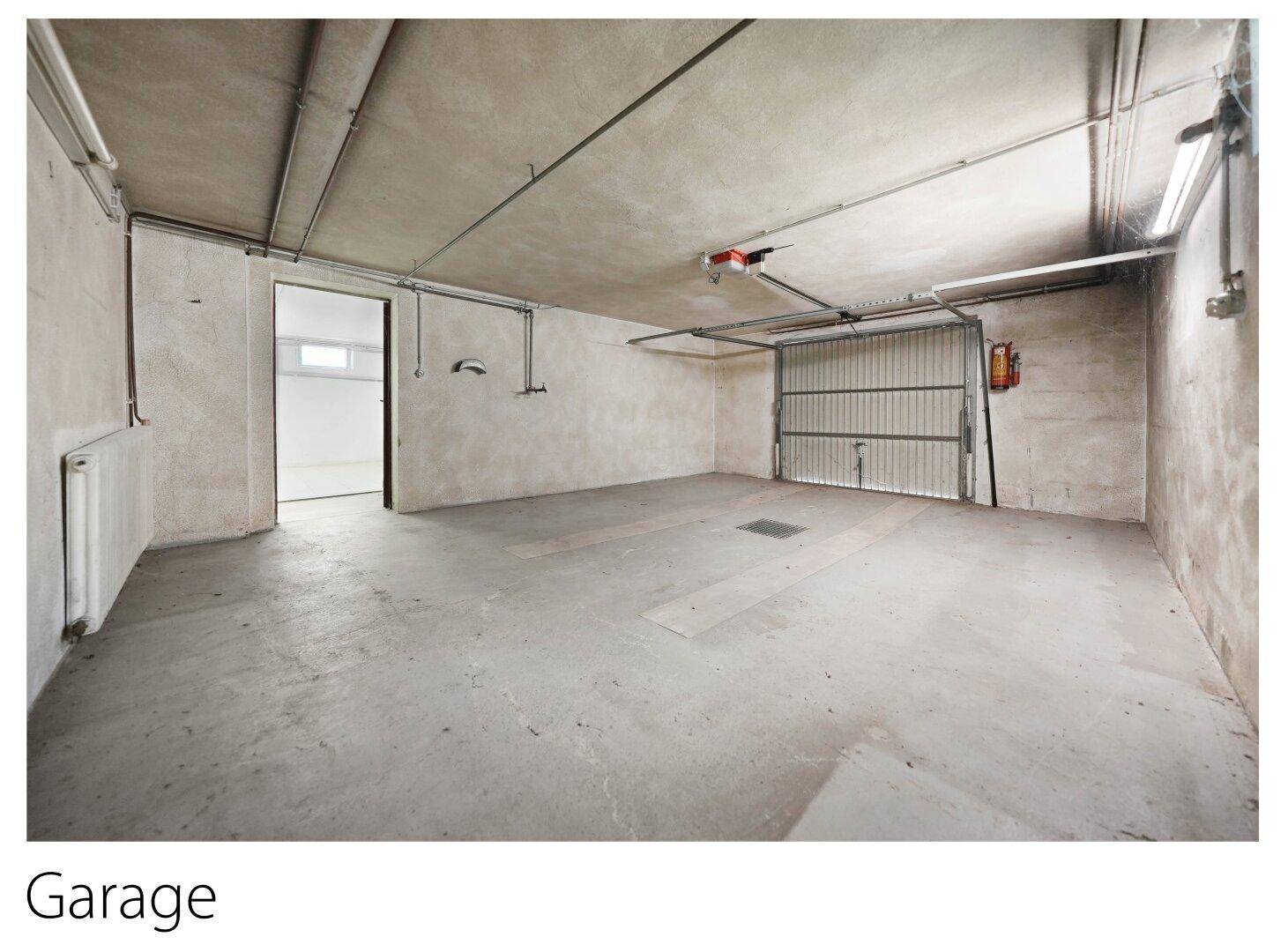 Geräumige Garage im Untergeschoss mit Betonboden und Rolltor.