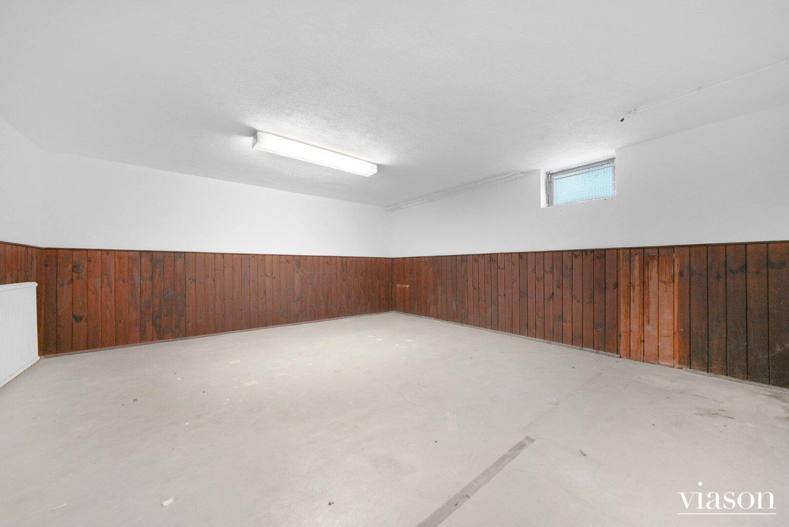 Kellerraum mit Holzvertäfelung an den Wänden und einem kleinen Fenster.