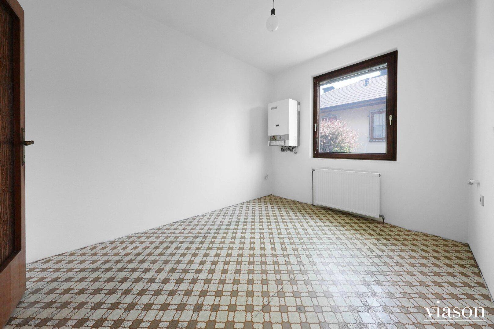 Leerer Raum mit Heizungsanlage und Fenster, bereit für individuelle Gestaltung.