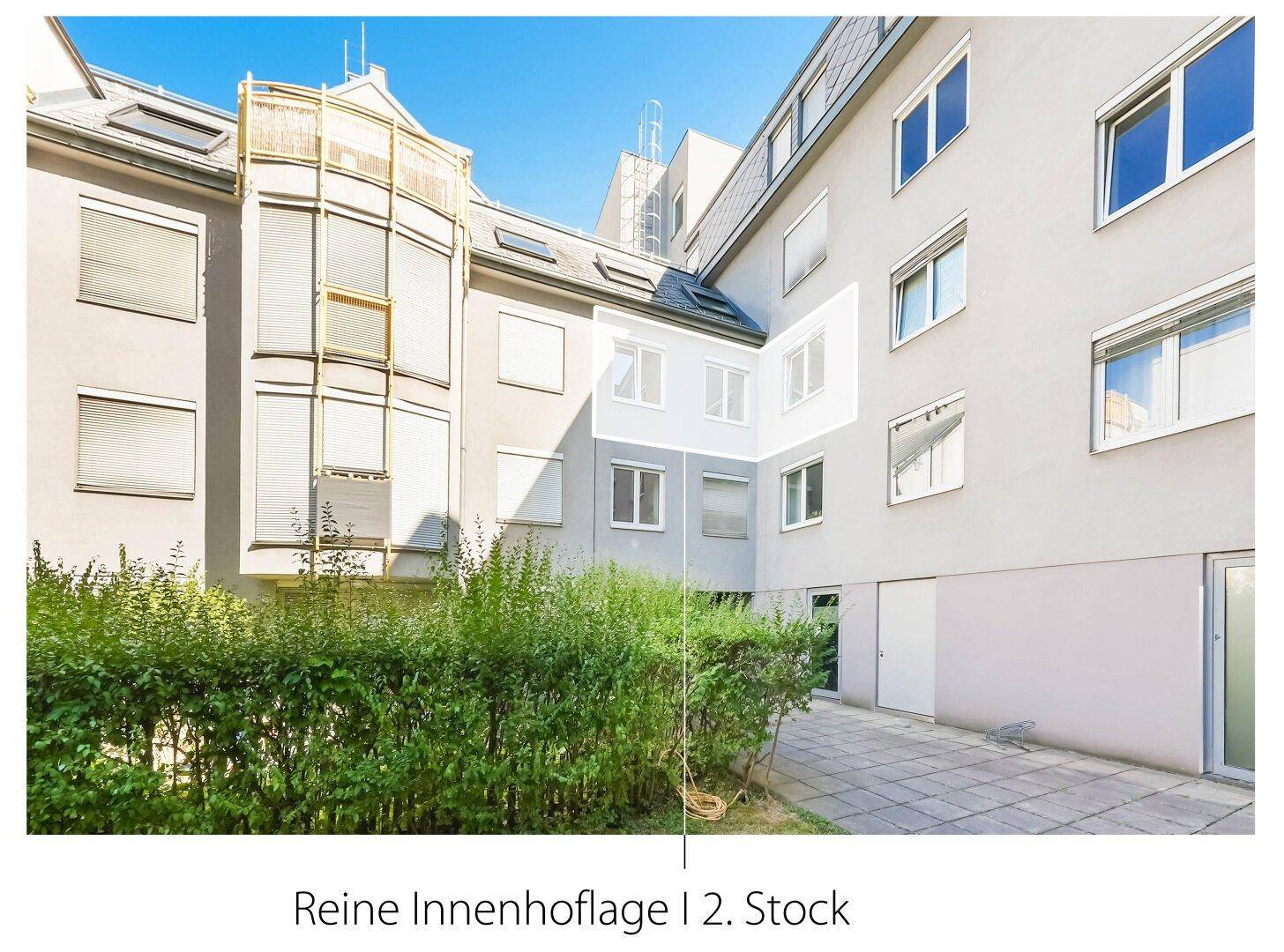 Ruhiger Innenhof mit gepflastertem Weg und grünen Hecken, umgeben von Gebäuden.