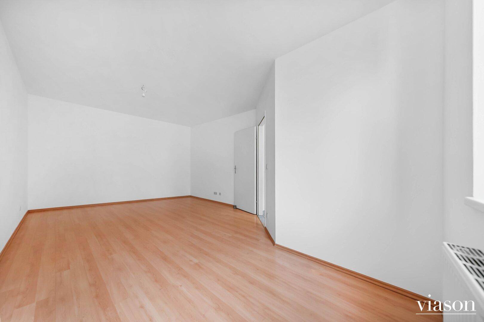 Geräumiges, leeres Zimmer mit hellem Parkettboden und sauber gestrichenen Wänden.