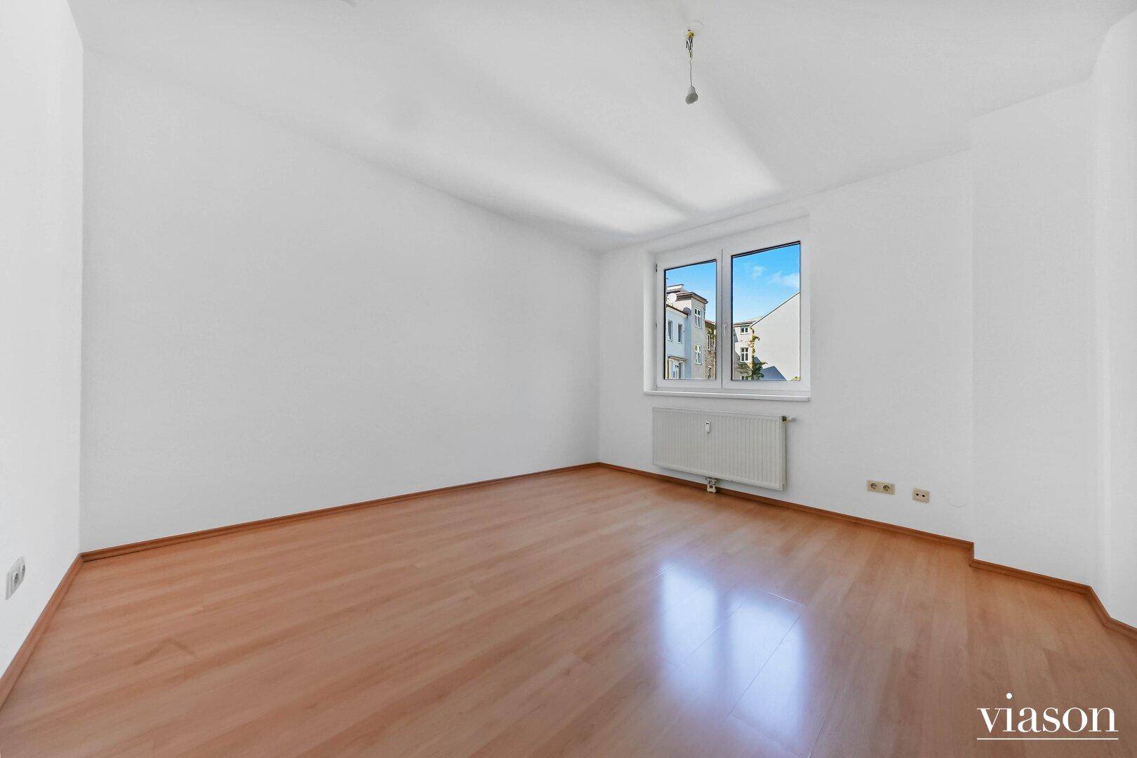 Geräumiges, leeres Zimmer mit hellem Parkettboden und sauber gestrichenen Wänden.