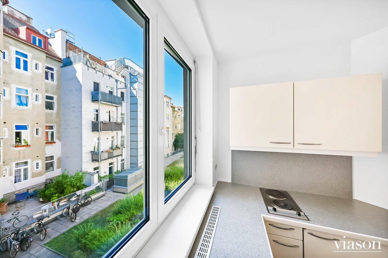Blick aus dem Küchenfenster auf einen begrünten Innenhof mit Fahrradabstellplätzen und umliegenden Gebäuden.