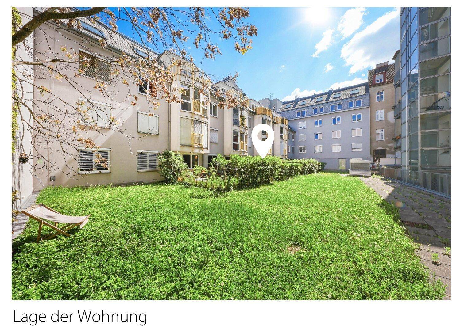 Sonniger Innenhof mit großer Rasenfläche und Bäumen, umgeben von Wohngebäuden.