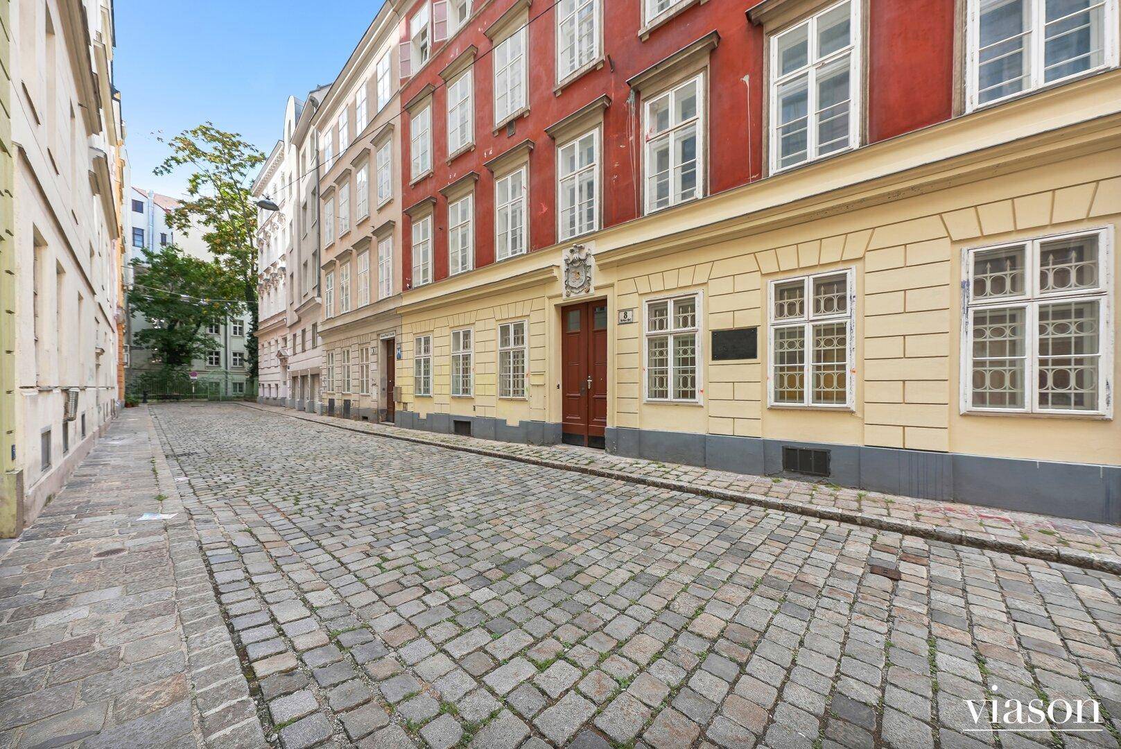 Historische Kopfsteinpflasterstraße mit farbigen Altbaufassaden in einer Wiener Gasse.