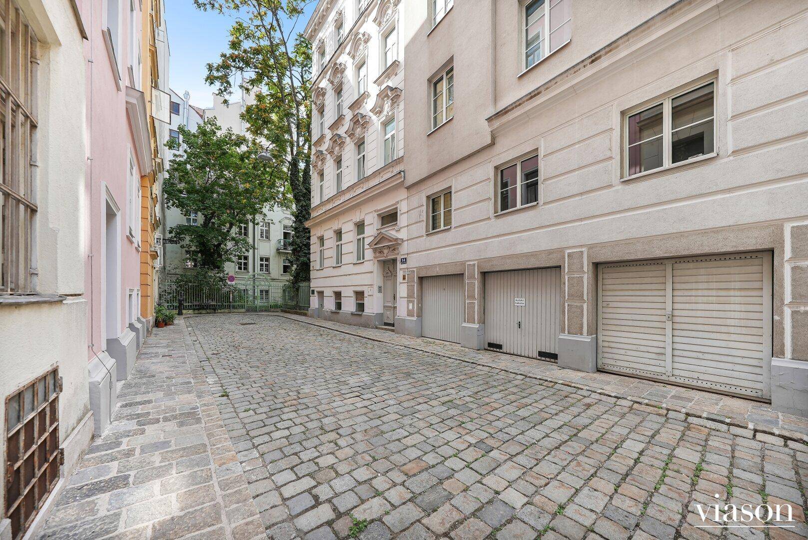 Kopfsteinpflastergasse mit Altbauten und Garagentoren in einem städtischen Umfeld.