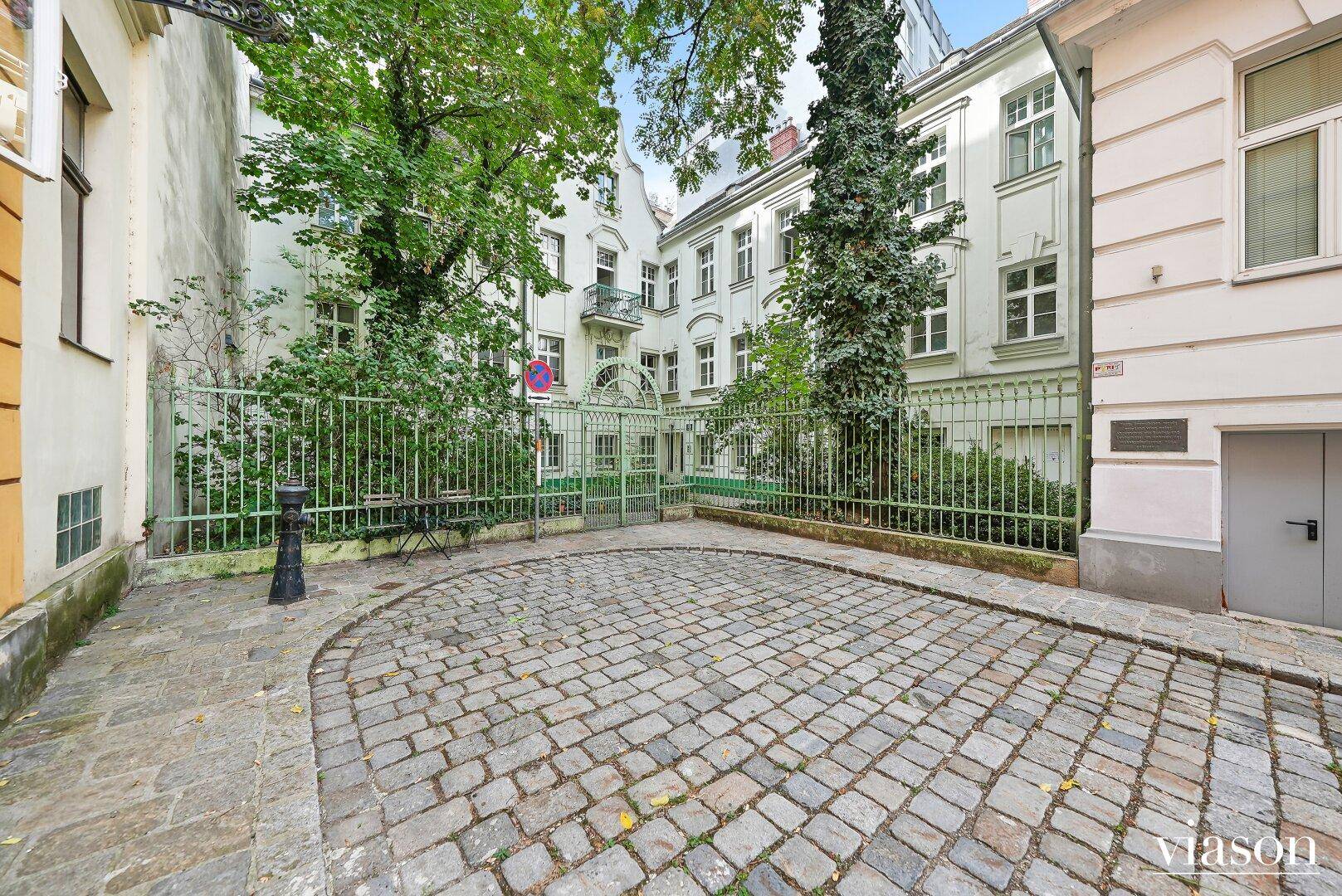 Blick auf einen begrünten Innenhof mit Kopfsteinpflaster und historischen Gebäuden.