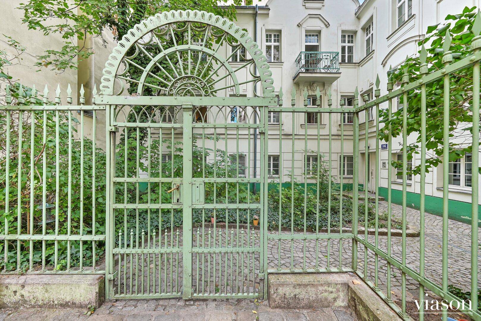 Detailansicht eines kunstvollen schmiedeeisernen Tores, das zu einem Innenhof führt.