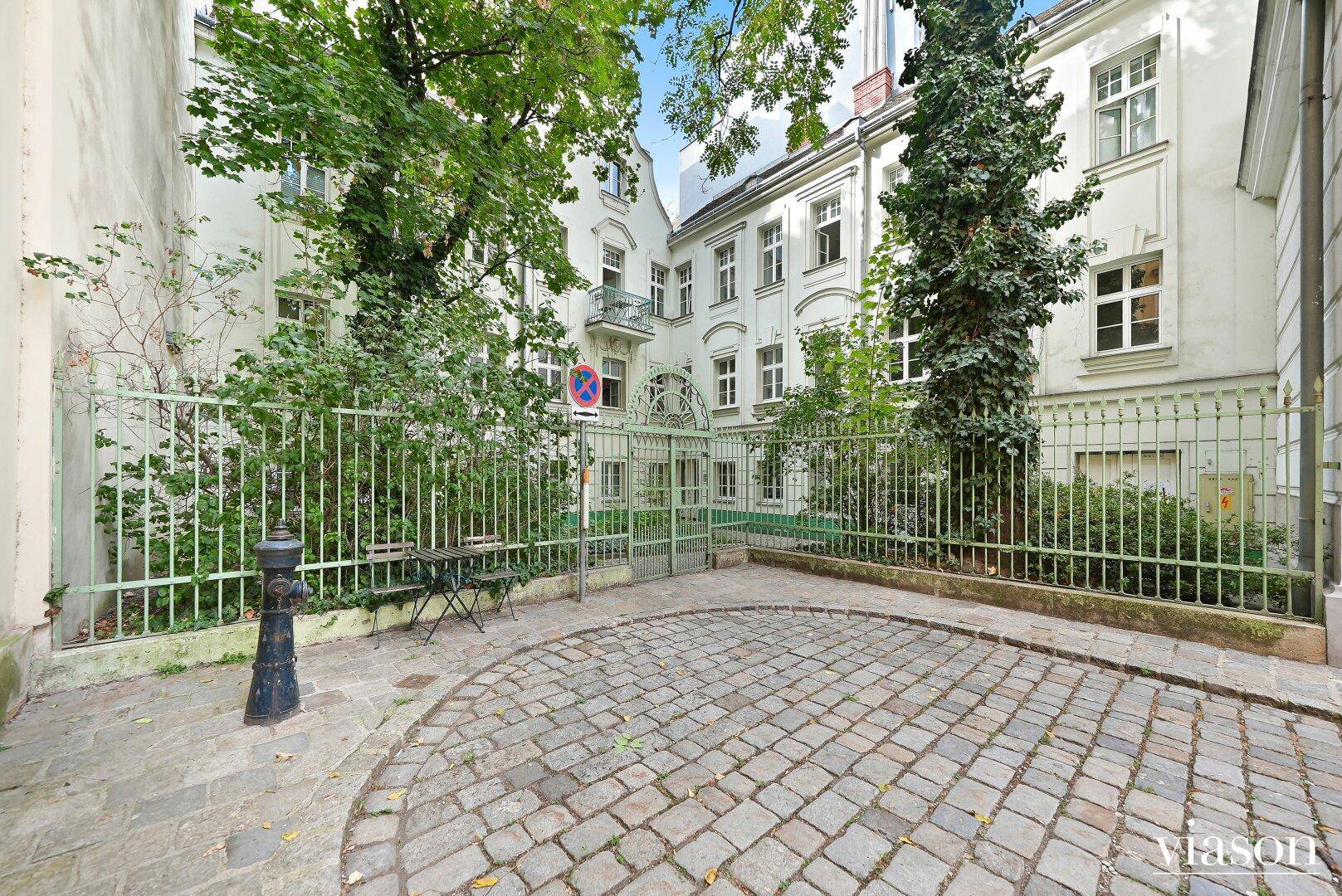 Historischer Innenhof mit Kopfsteinpflaster und üppiger Begrünung, umgeben von Altbauten.