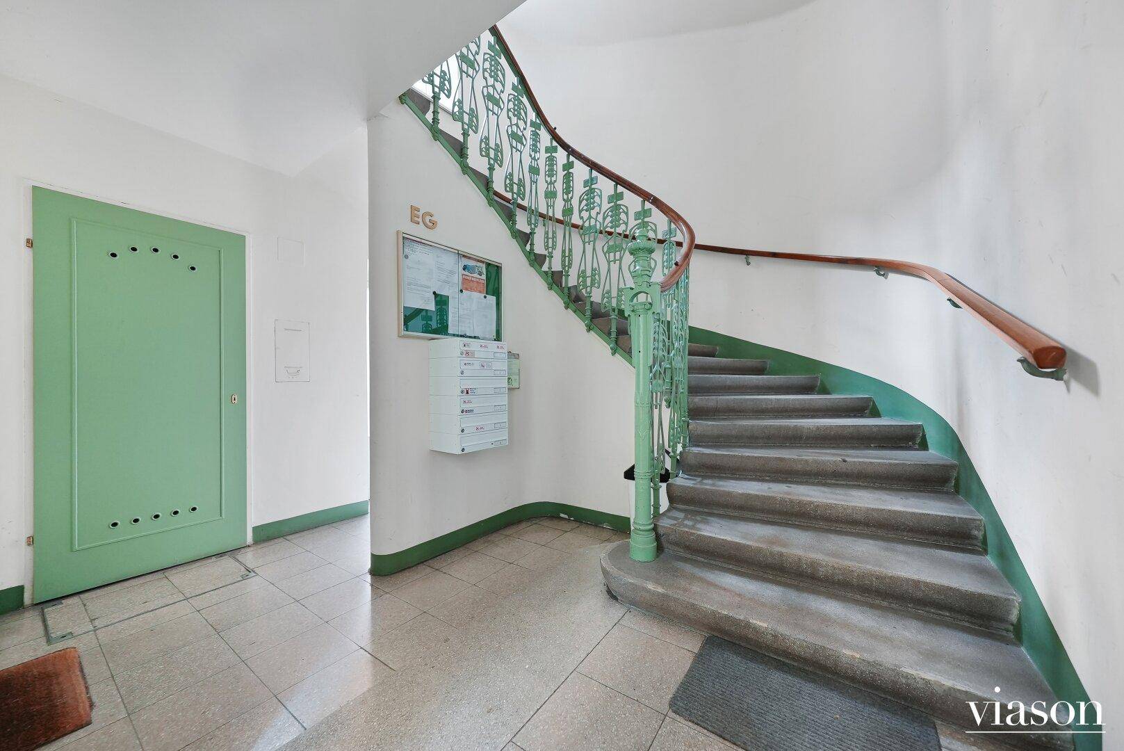Historisches Treppenhaus mit schmiedeeisernem Geländer und Steinstufen in einem Altbau.