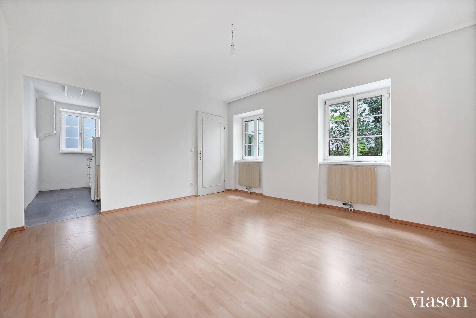 Helles, leeres Zimmer mit Parkettboden und weißen Wänden, bereit zur individuellen Gestaltung.