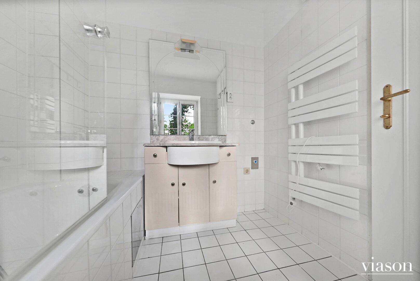 Komplettes Badezimmer mit Badewanne, Waschtisch, Spiegel und praktischem Handtuchheizkörper.