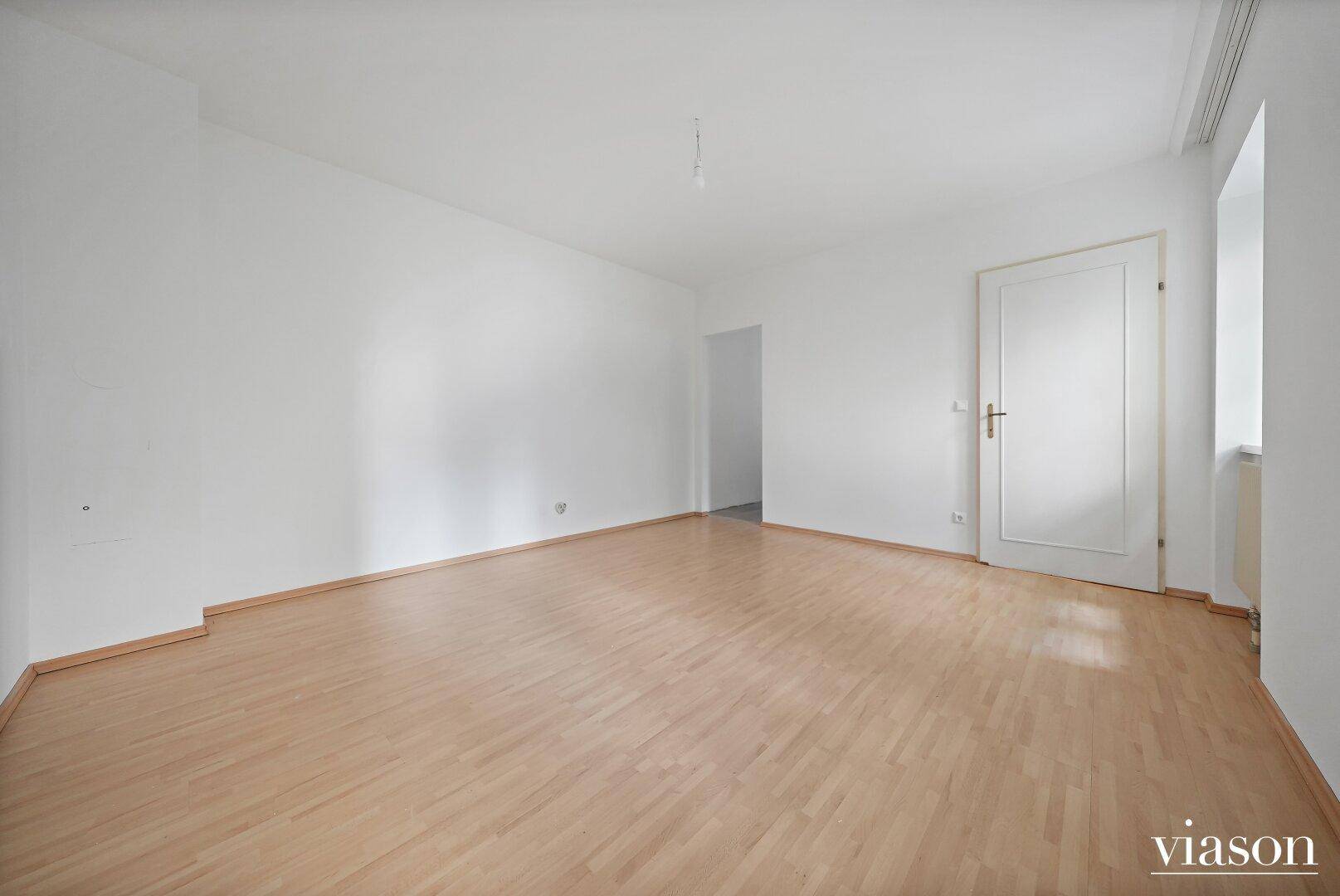 Leeres Zimmer mit hellem Parkettboden und weiß gestrichenen Wänden, bietet vielseitige Nutzungsmöglichkeiten.
