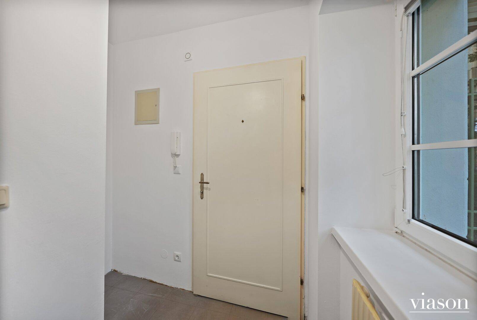 Eingangsbereich einer Wohnung mit weißer Tür und Fenster, das Licht hereinlässt.