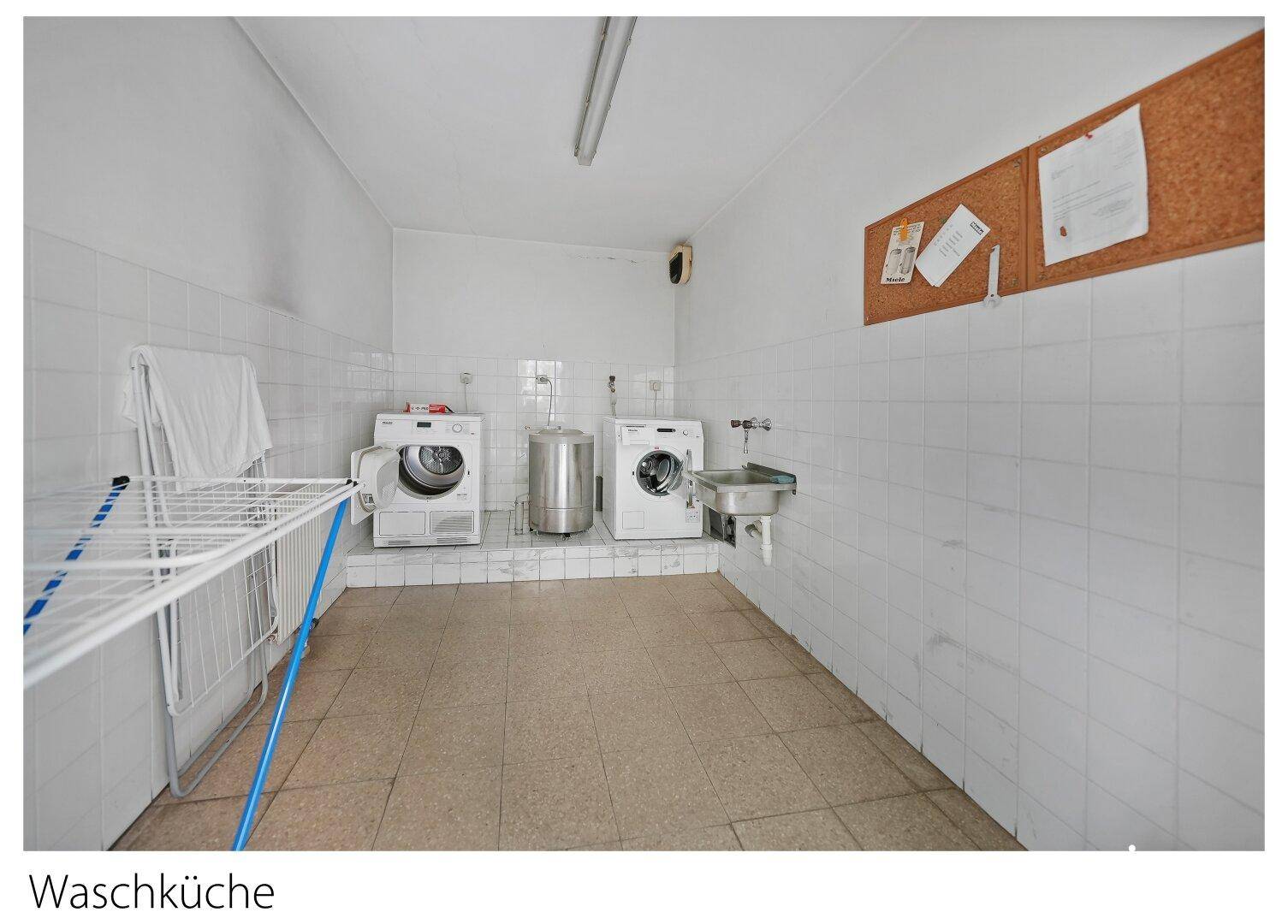 Gemeinschaftliche Waschküche mit Waschmaschinen, Trockner und Waschbecken für die Bewohner.
