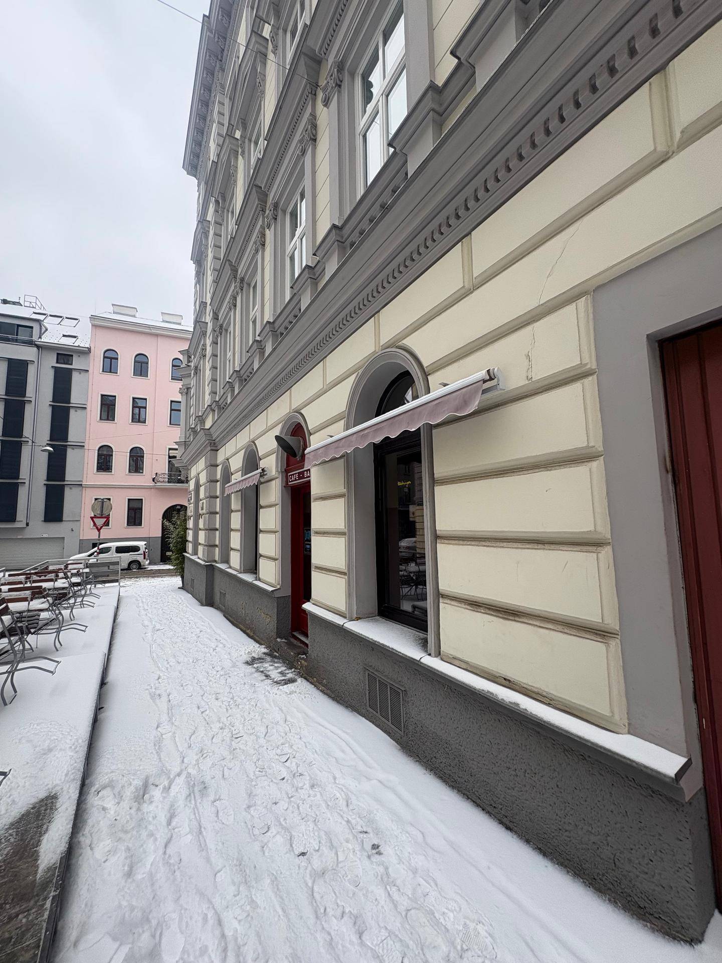 Historische Gebäudefassade mit Markise und verschneiter Straße im Winter.