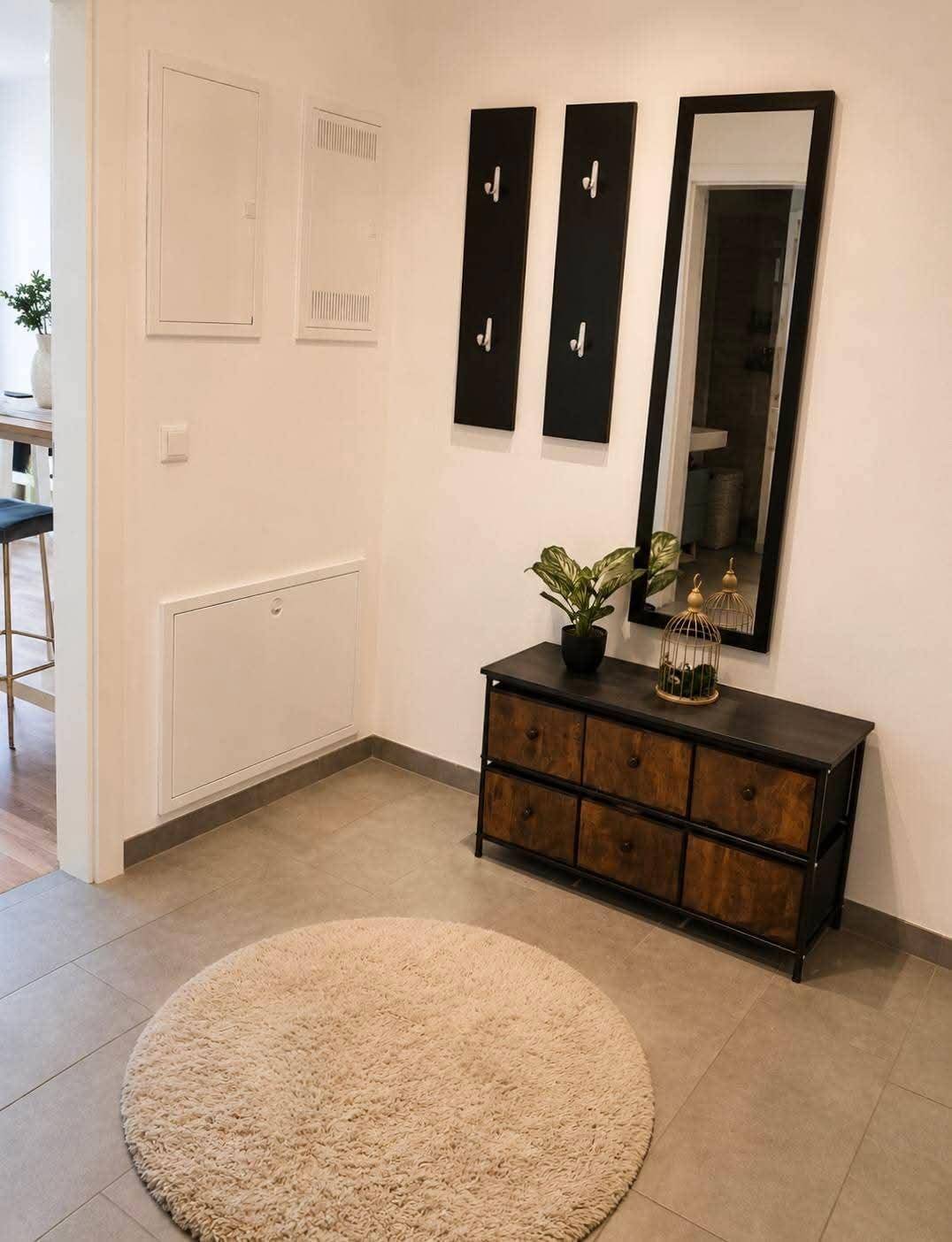 Eingangsbereich mit Fliesenboden, Garderobe und einem dekorativen Spiegel.