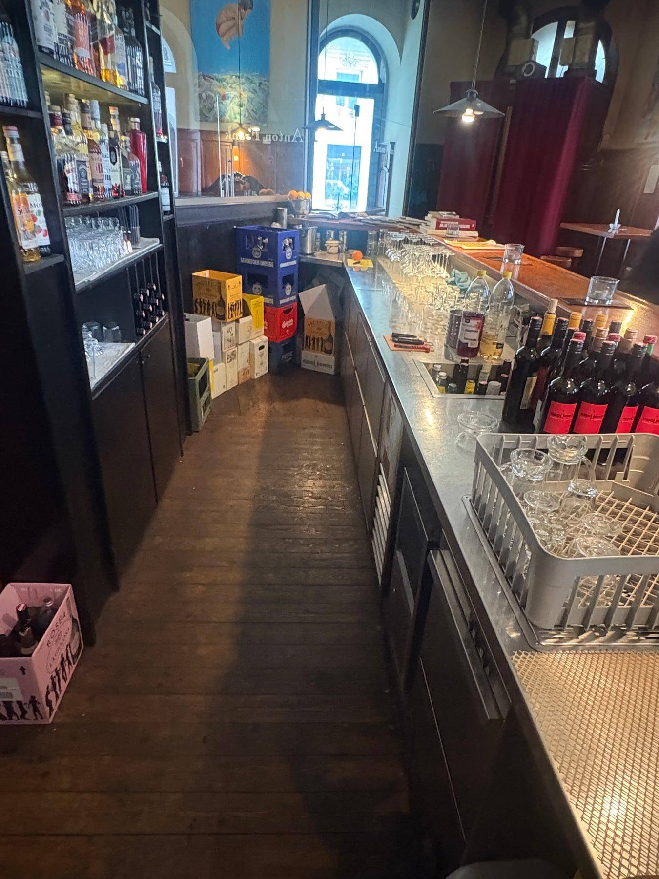Lagerbereich hinter der Bar mit Getränkekisten, Flaschenregalen und Gläsern.