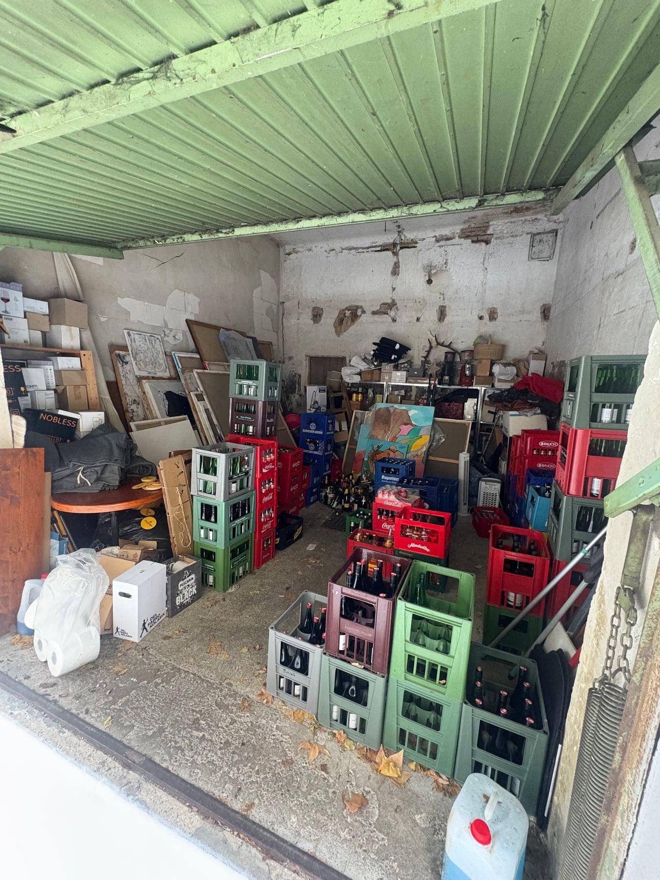Innenansicht einer Garage, die als Lagerraum für Getränkekisten und andere Gegenstände dient.