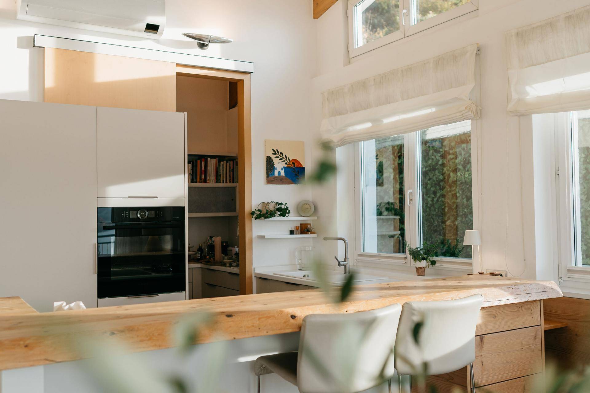 Moderne Küche mit Holzarbeitsplatte, integriertem Backofen und begehbarer Speisekammer.