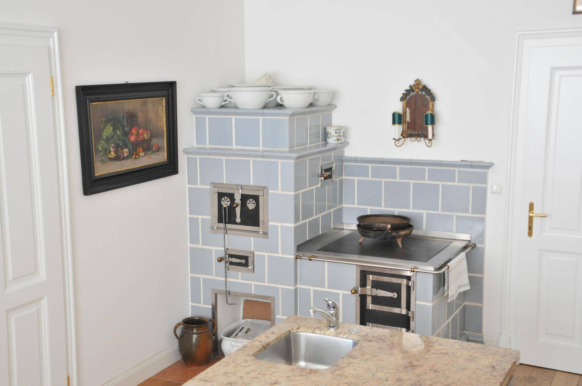 Rustikale Küche mit einem traditionellen Kachelofen und einer Arbeitsplatte aus Granit, ideal für gemütliches Kochen.