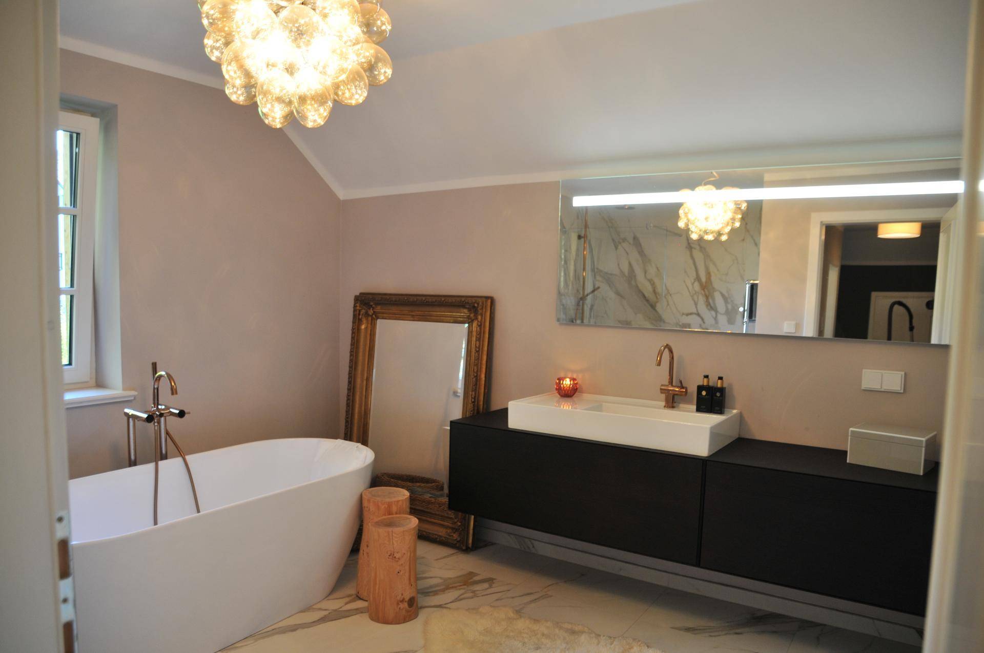 Elegantes Badezimmer mit freistehender Badewanne, modernem Waschtisch und großem Spiegel.