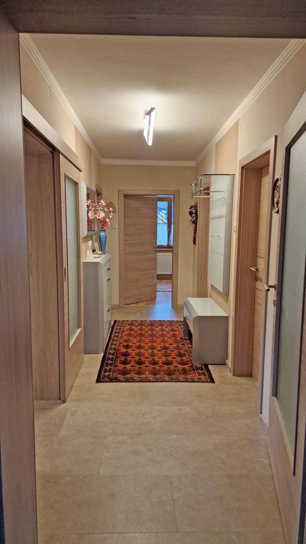 Heller Eingangsbereich mit Fliesenboden, Garderobe und Blick in angrenzende Räume.