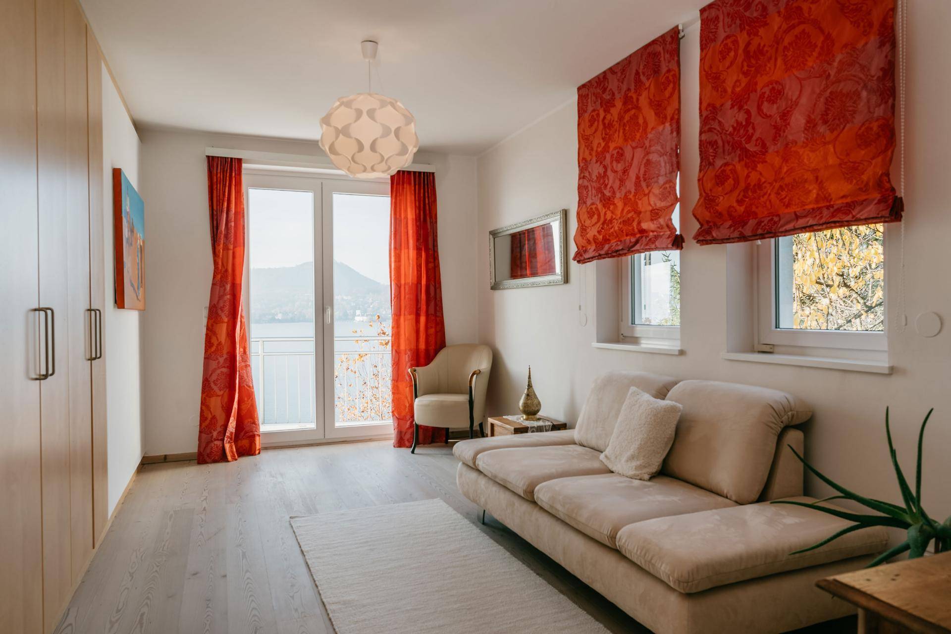 Gemütliches Schlafzimmer mit Sofa, Einbauschränken und Zugang zum Balkon.