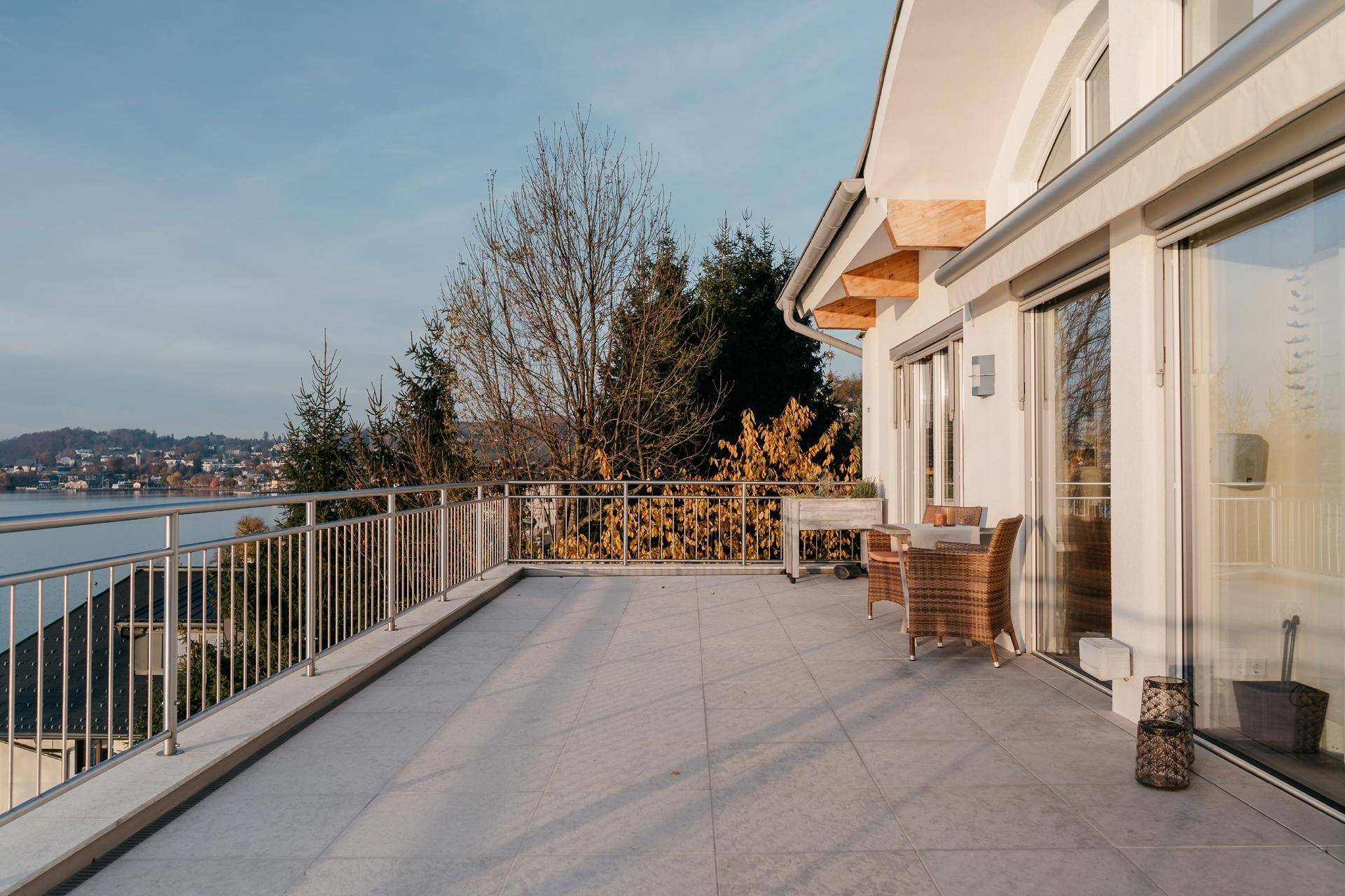 Große Terrasse mit Rattanmöbeln und weitem Blick über den See und die Landschaft.