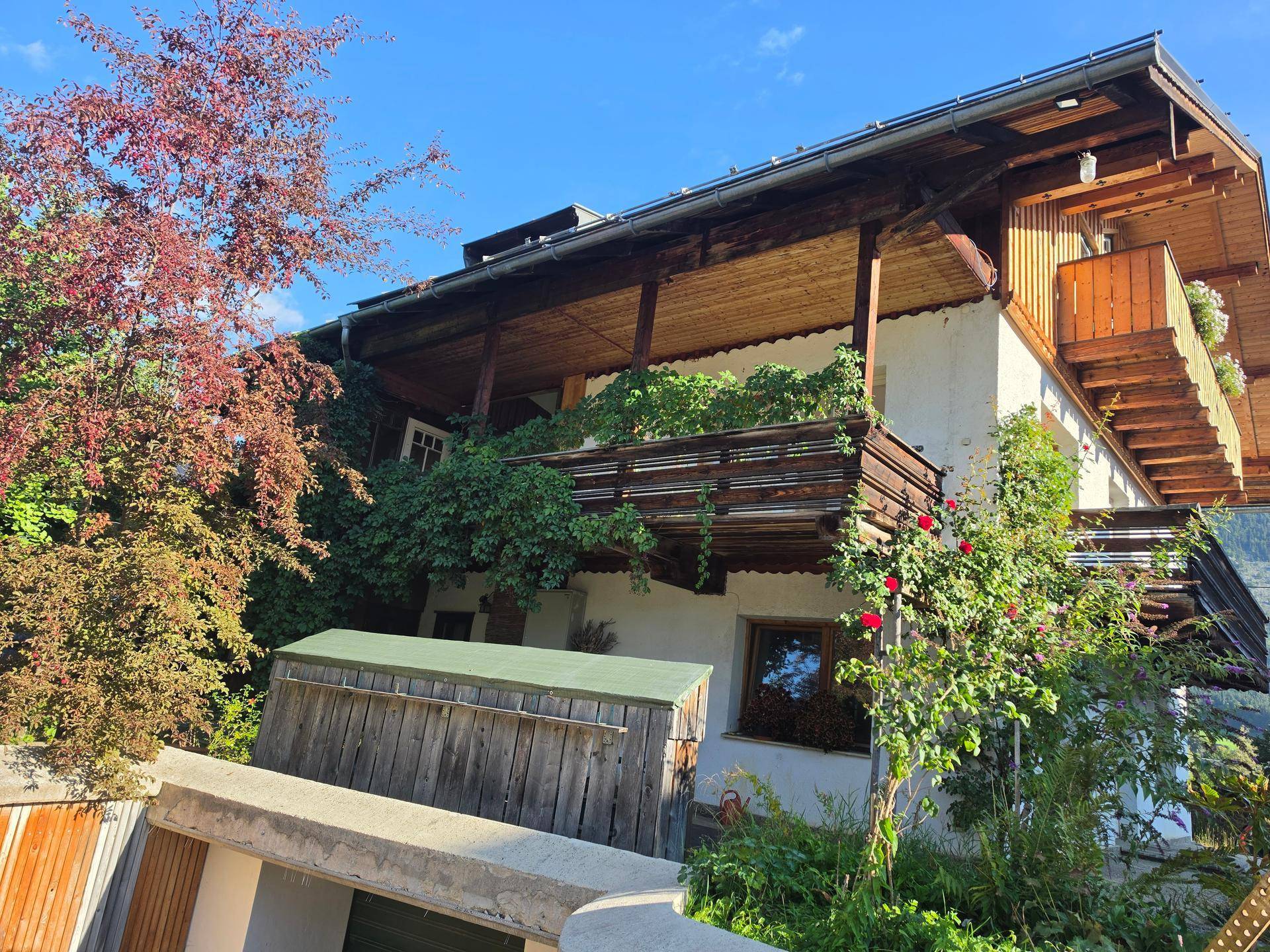 Traditionelles Haus mit mehreren Holzbalkonen und üppiger Bepflanzung an der Fassade.