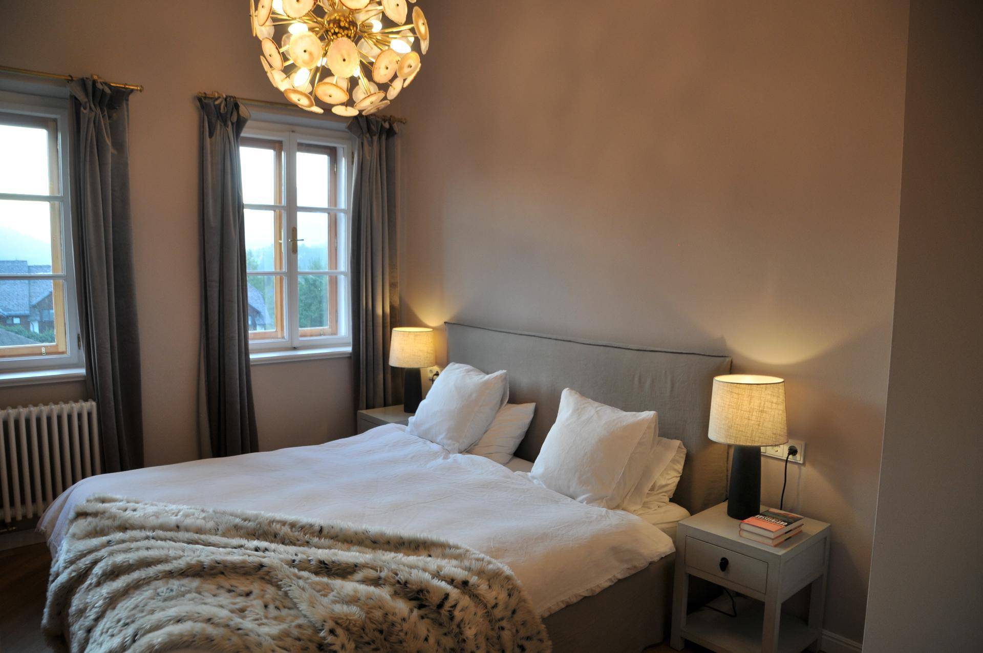 Gemütliches Schlafzimmer mit Doppelbett, Nachttischen und einem auffälligen Kronleuchter.