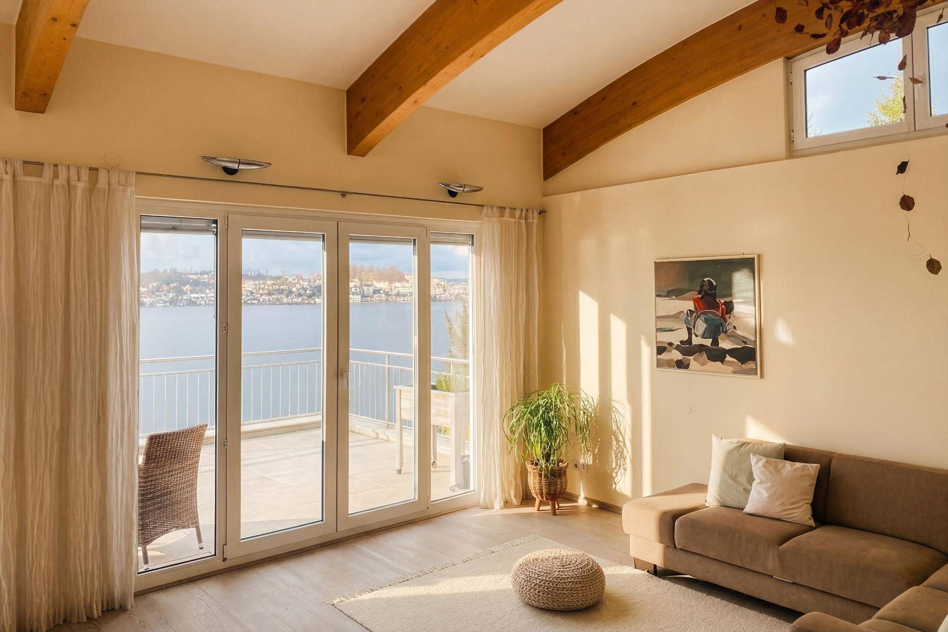 Helles Wohnzimmer mit Balkonzugang, Holzbalken und weitem Blick auf den See.