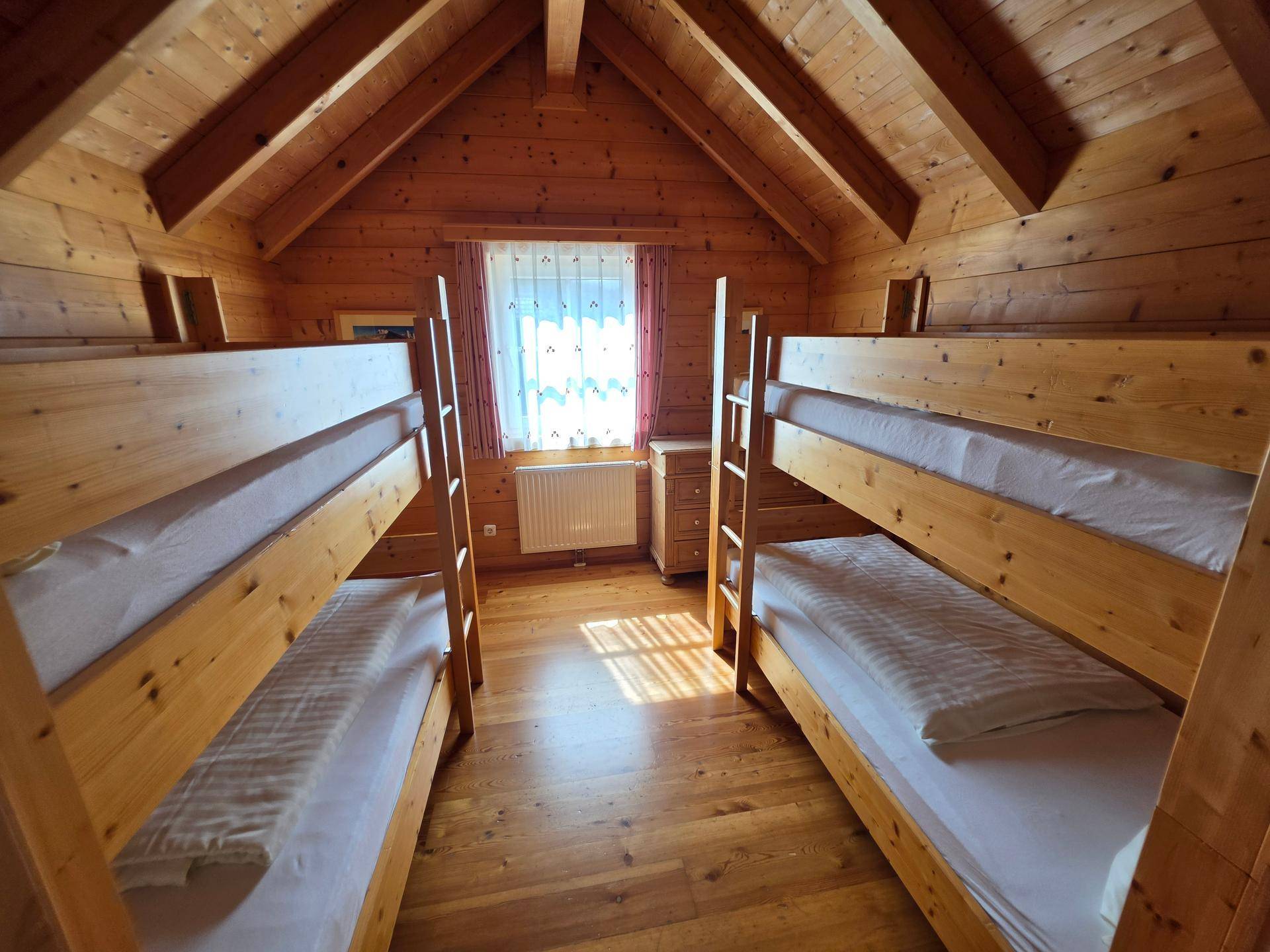 Kinderzimmer im Dachgeschoss mit zwei Etagenbetten, Holzboden und schrägen Decken, hell und funktional.