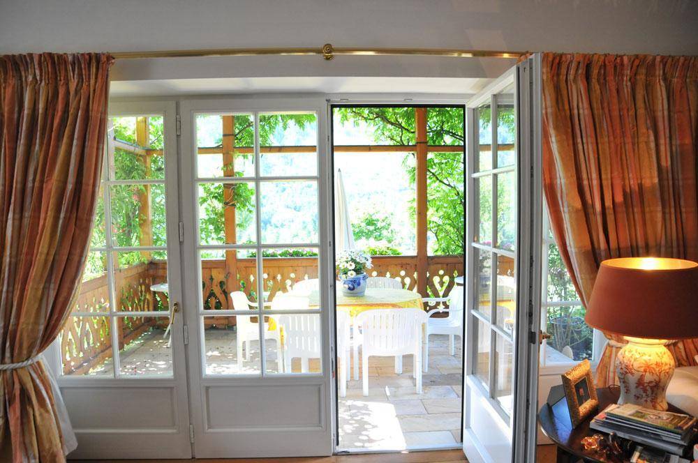 Heller Wohnbereich mit Zugang zu einer sonnigen Terrasse, umgeben von üppigem Grün und mit Blick in die Natur.