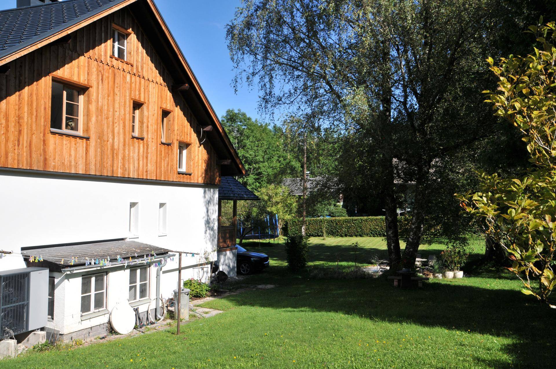 Großer, gepflegter Gartenbereich mit Rasenfläche und altem Baumbestand hinter dem Haus.
