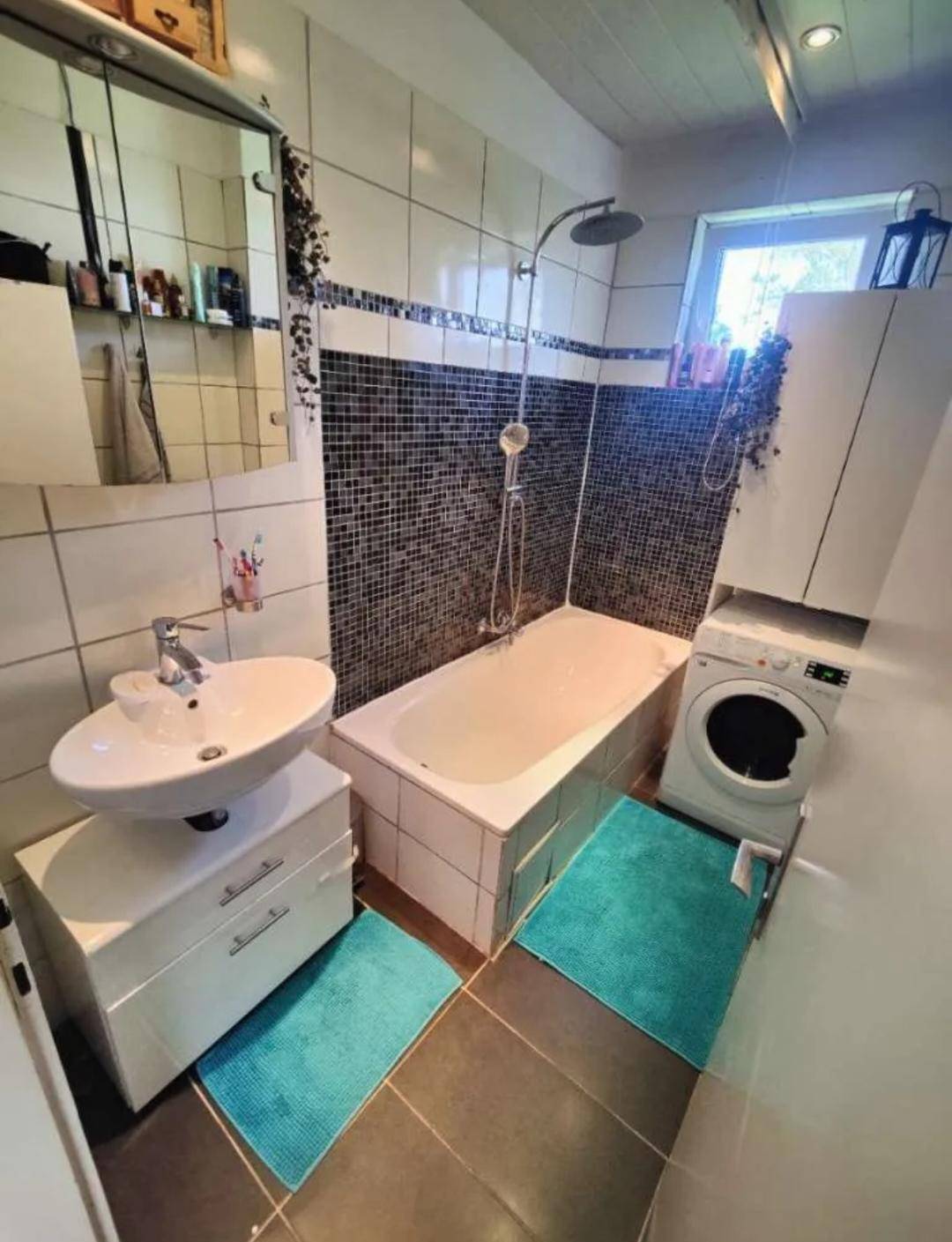 Funktionales Badezimmer mit Badewanne, Dusche, Waschbecken und Mosaikfliesen.