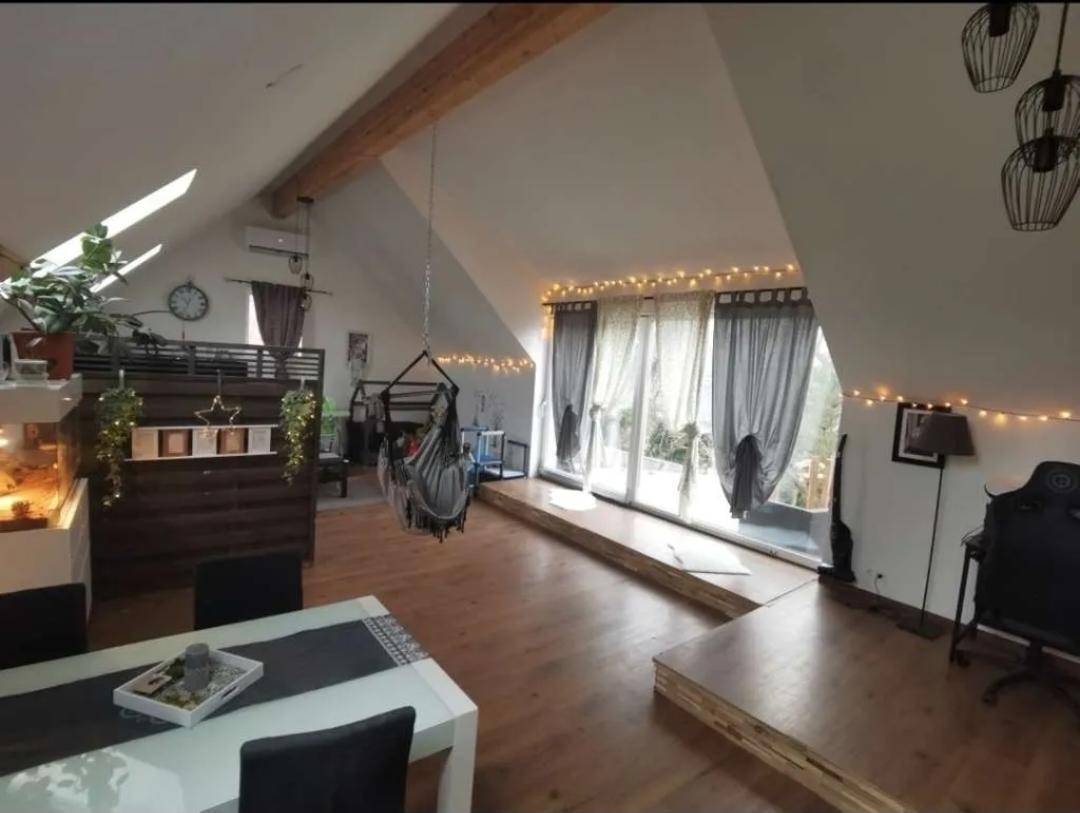 Heller Wohn- und Essbereich im Dachgeschoss mit Holzbalken und großen Fenstern.