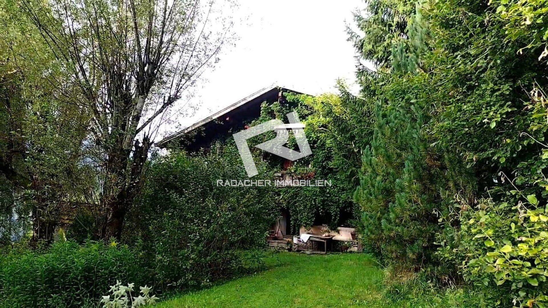 Großzügiger, naturbelassener Garten umgibt das traditionelle Haus, eingebettet in grüne Landschaft.