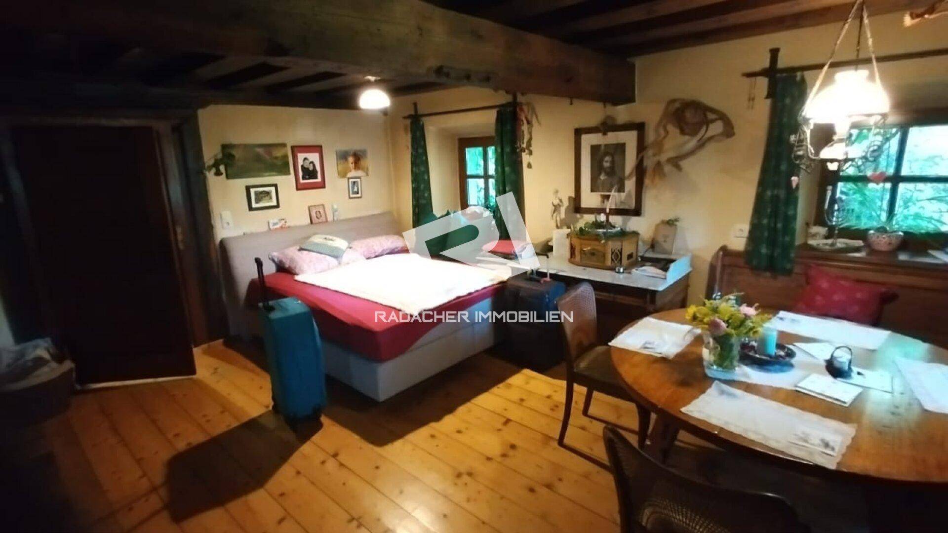 Gemütlicher Wohnbereich mit Holzboden, Bett und Esstisch, dekoriert im traditionellen Stil.