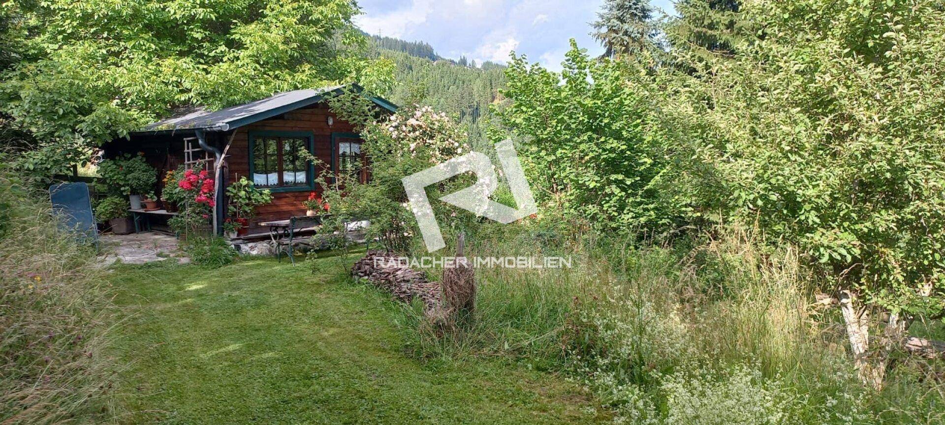 Gemütliches Holzhaus im Grünen, umgeben von einem weitläufigen Garten mit Bergblick.