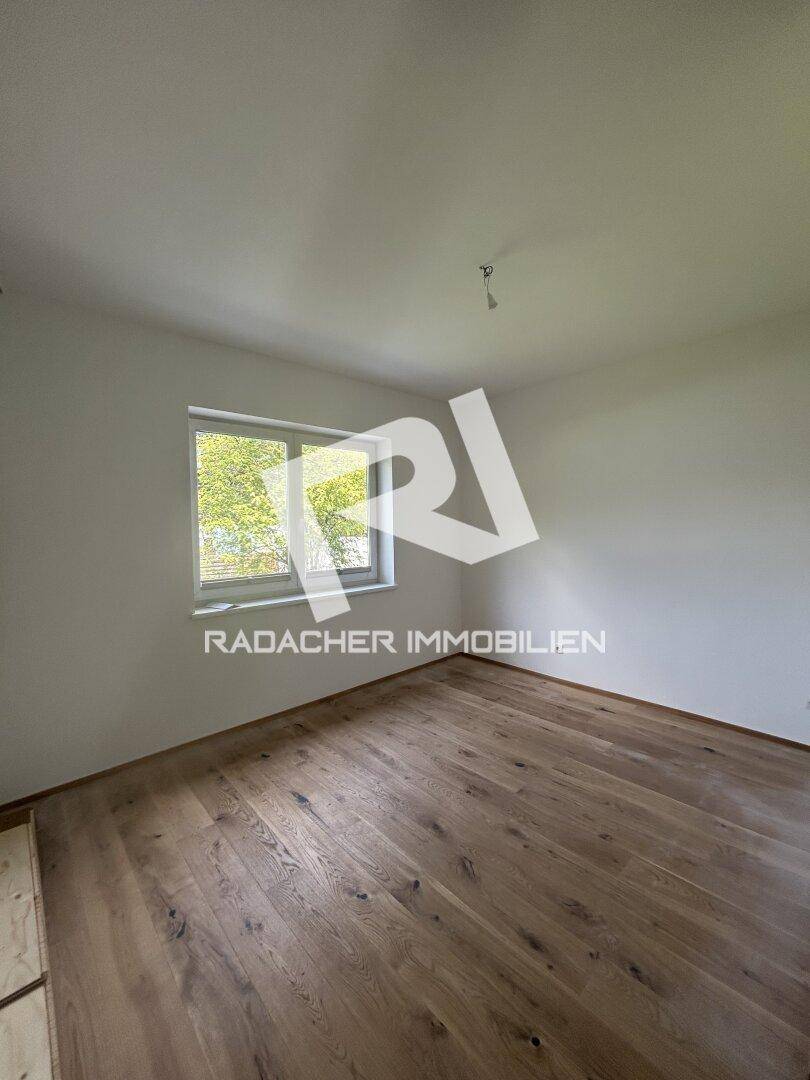 Unmöbliertes Zimmer mit neuem Holzboden und Fenster, das viel Tageslicht hereinlässt.