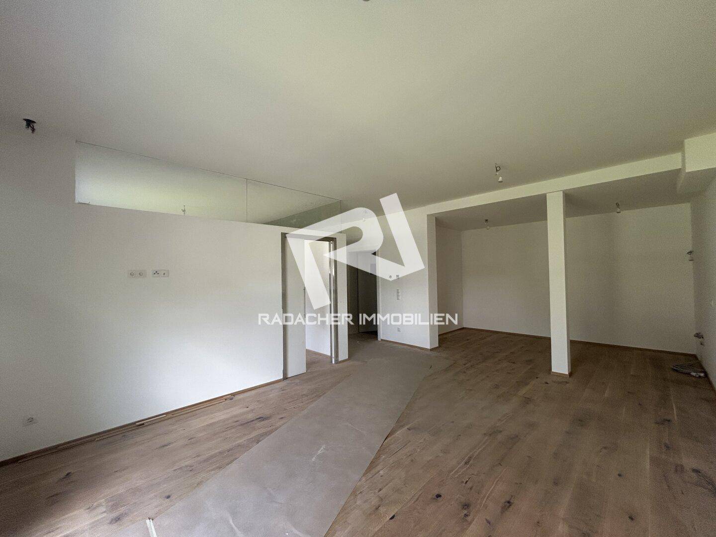 Unfertiger Innenraum mit Holzboden und mehreren Türöffnungen, der auf den Ausbau wartet.