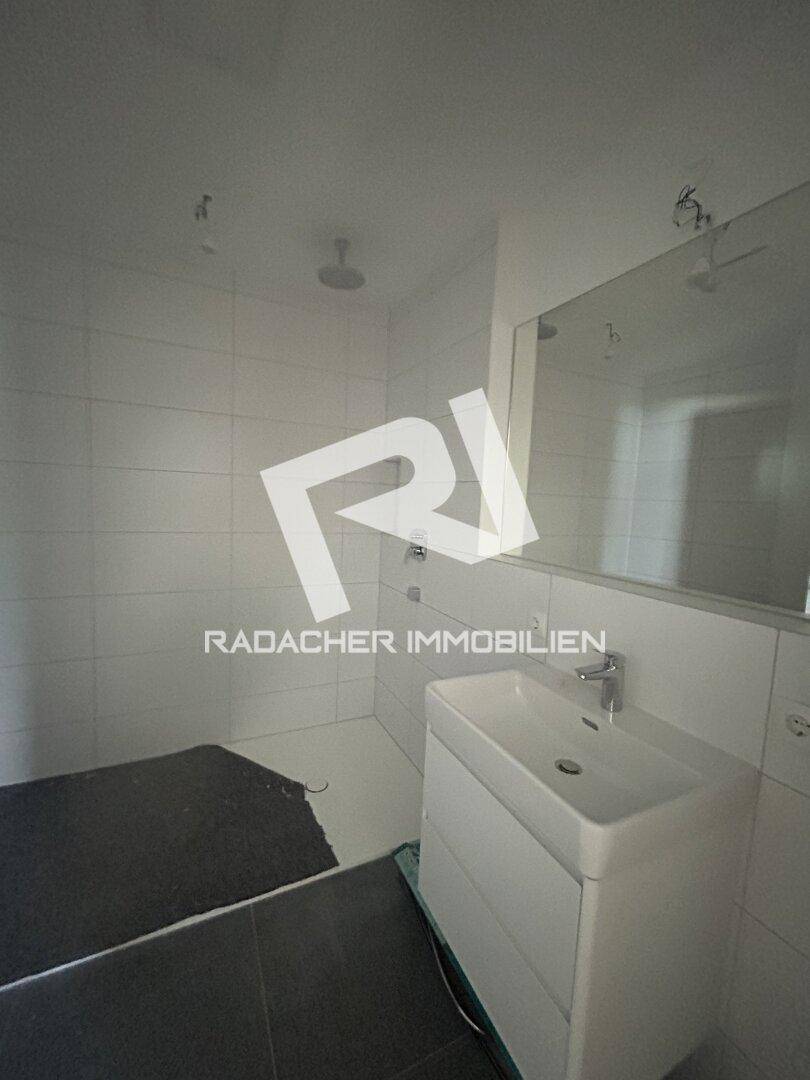 Modernes Badezimmer mit Duschbereich, Waschbecken und großem Spiegel.