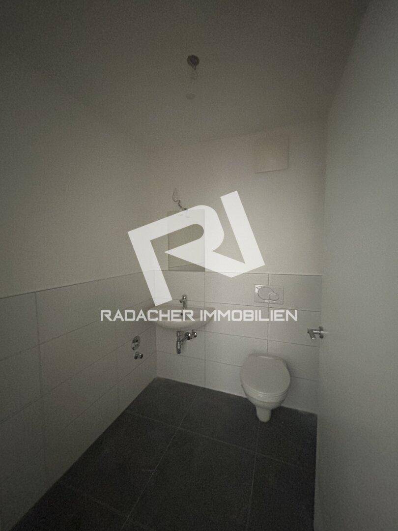 Funktionelles Gäste-WC mit Wand-WC und kleinem Waschbecken, in neutralen Farben gehalten.