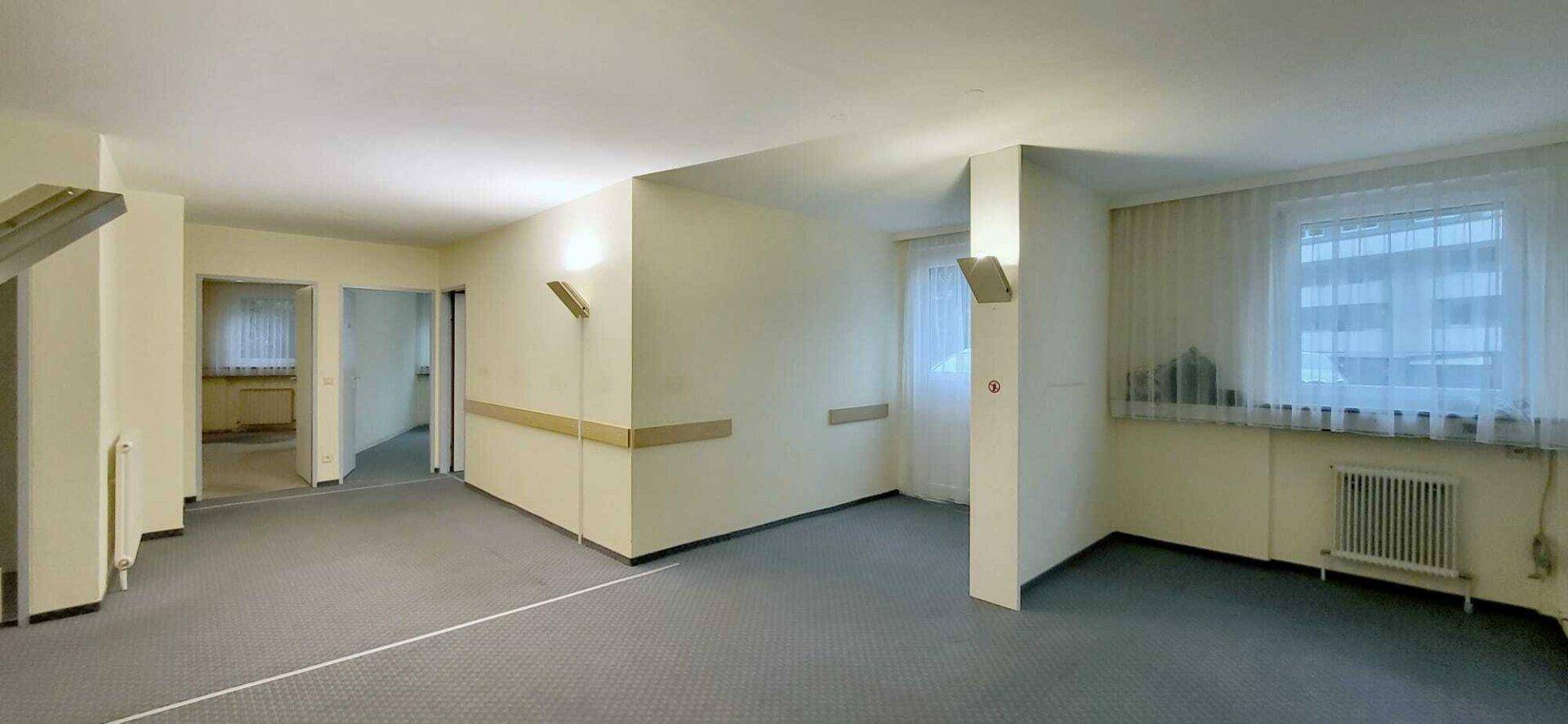 Großer, heller Flurbereich mit Fenstern, Teppichboden und Zugang zu weiteren Räumen.