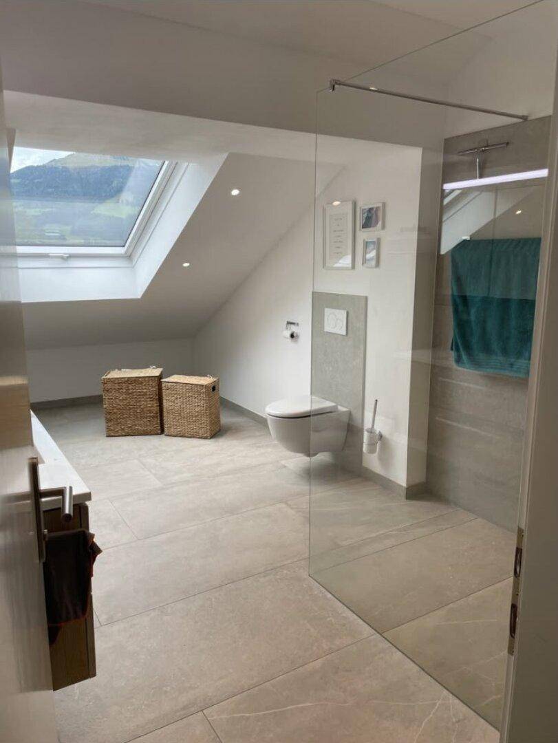 Helles, modernes Badezimmer im Dachgeschoss mit begehbarer Dusche und großem Dachfenster.