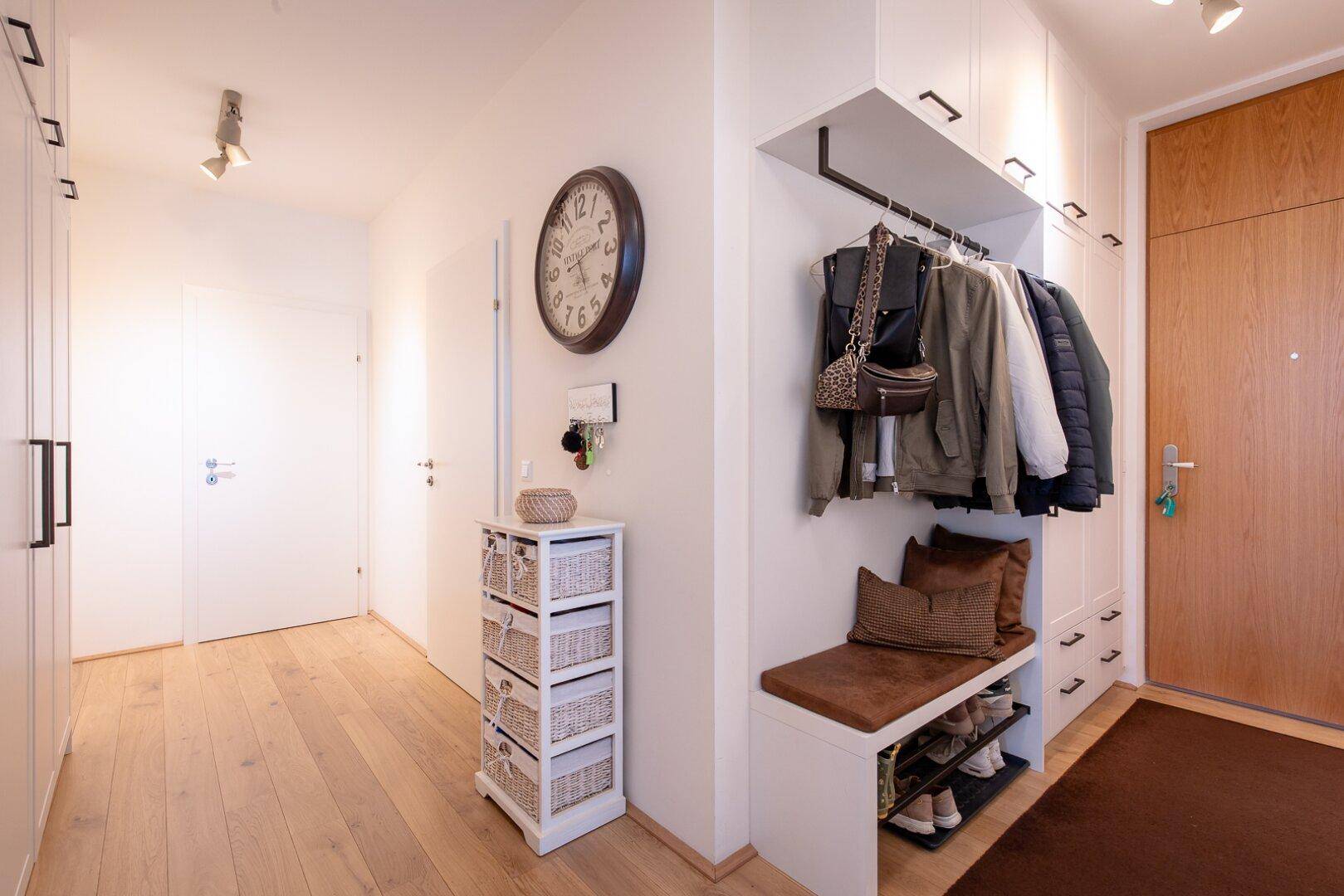 Geräumiger Flur mit Einbauschränken, Sitzbank und Holzboden, ideal für Garderobe.
